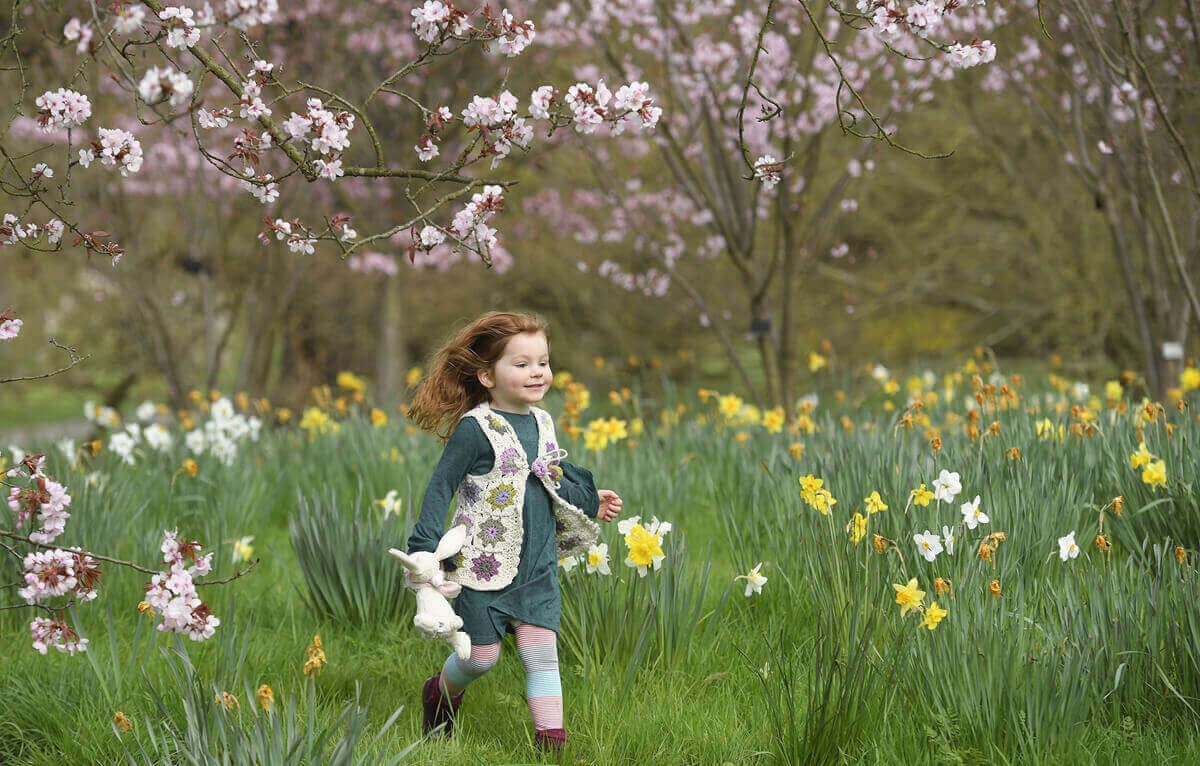 Ева играет среди весенних цветов в Кью-Гарденс в западном Лондоне