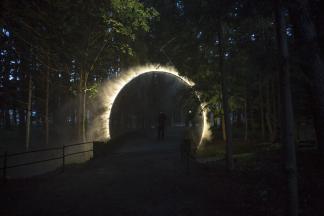 Кольцо водяной дымки окружает мост, пересекающий реку, на фестивале искусств Японских Альп